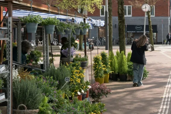 Eine Frau geht an der Auslage eines Blumengeschaefts vorbei