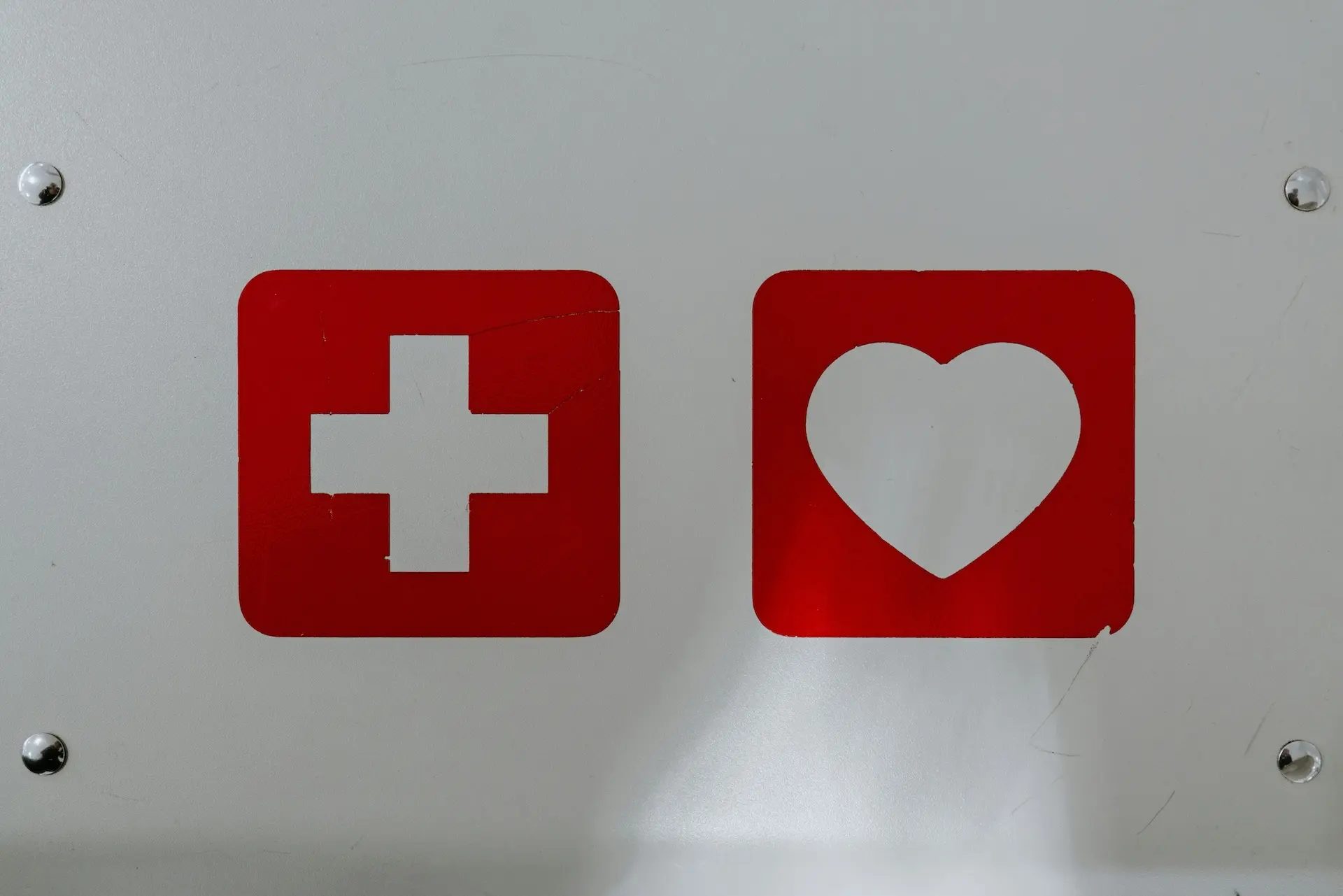 Bild zeigt die Logos von Erste-Hilfe – das typische Apothekenkreuz und ein weißes Herz auf rotem grund
