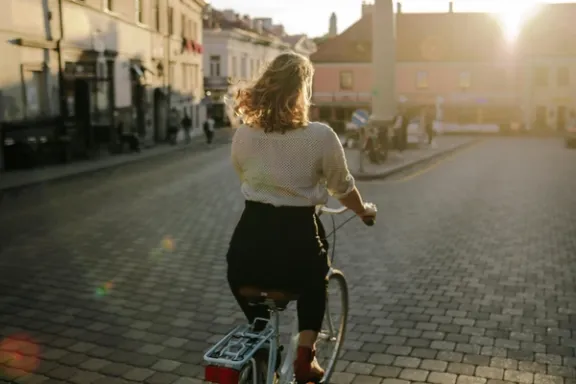 Frau fährt auf Fahrrad über einen Platz im Sonnenuntergang