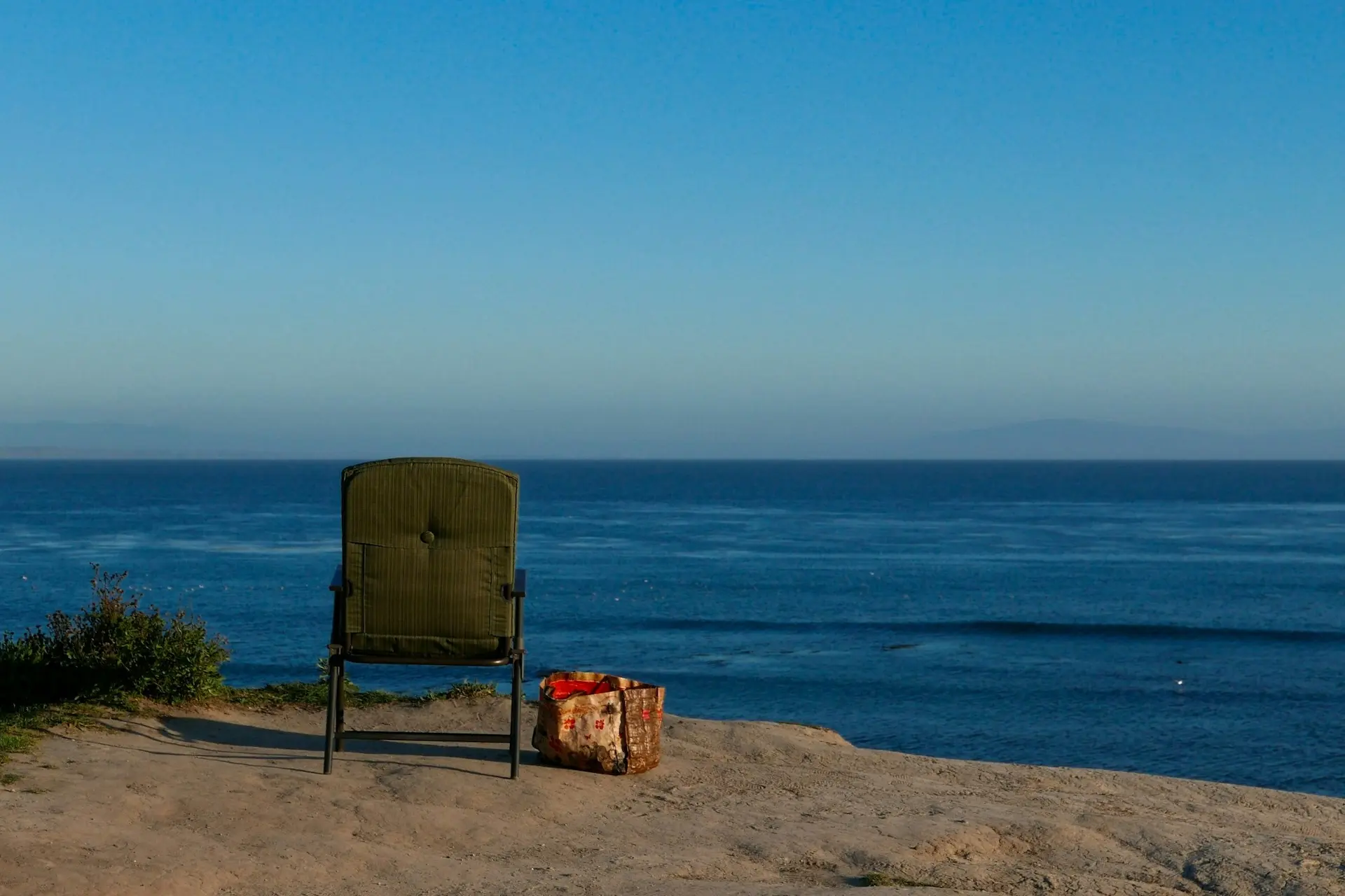 Auf einer Klippe steht ein Sessel mit Blick aufs Meer 