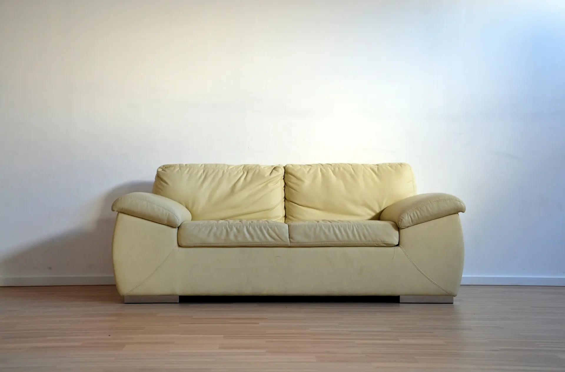 Bild von einer beigen Couch auf Parkettboden