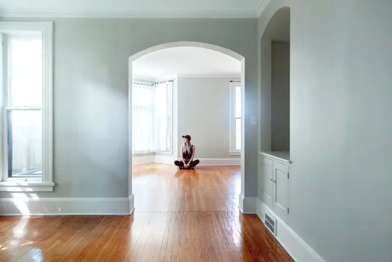 Person sitzt auf Boden von leerer Wohnung