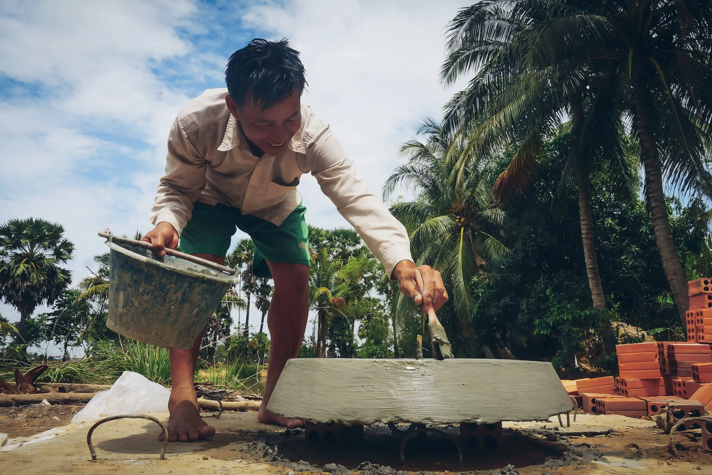 Mann baut Biogasanlage unter Palmen