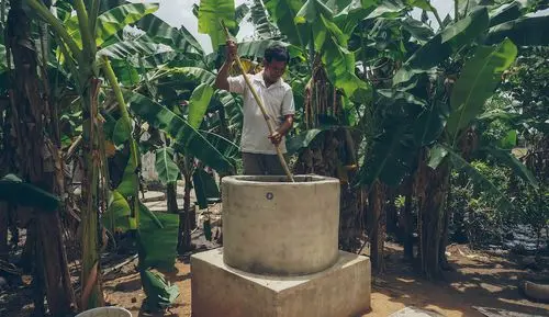 Ein Bauer in Kambodscha rührt ein Tierdung-Wasser-Gemisch in den Einfülltank einer kleinen Biogasanlage.